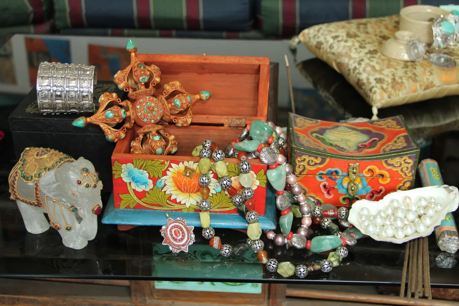 A silver cuff, beaded necklaces with silver beads, a gilded dorje and hand-painted wooden boxes from the Yak & Yeti range